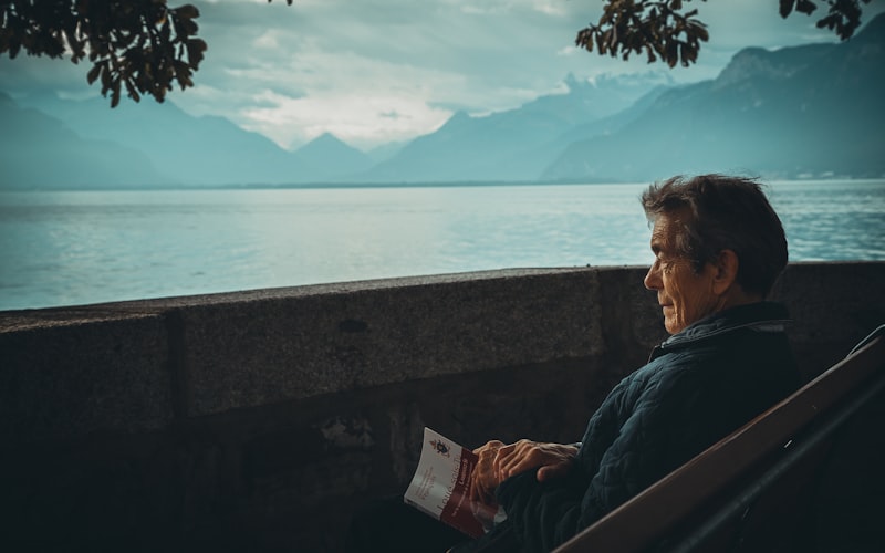 A person sitting quietly by a lake in soft light