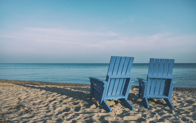 Two empty deck chairs facing a calm sea