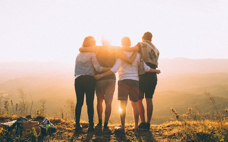 Family standing arm in arm watching the sunset over hills