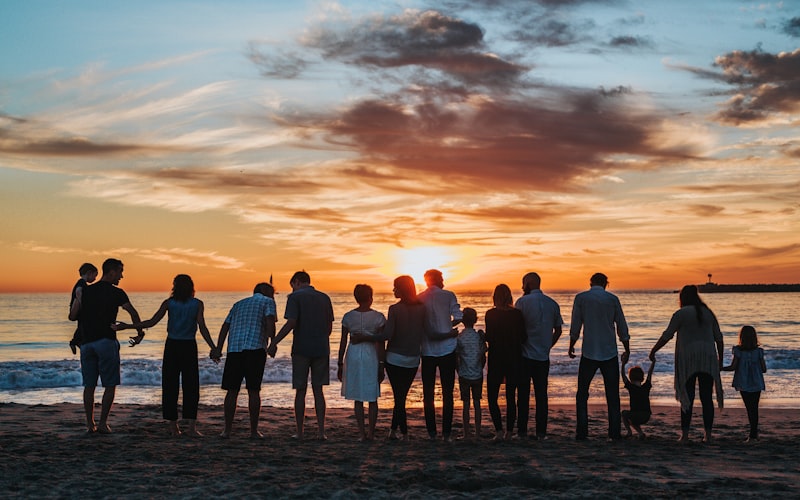 Three generations of a family walking together on a beach at sunset