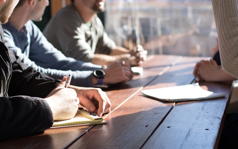 A discussion around a warm timber meeting table