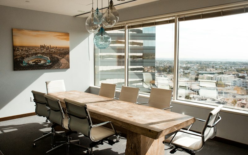 An empty meeting room with a timber table and chairs in soft daylight