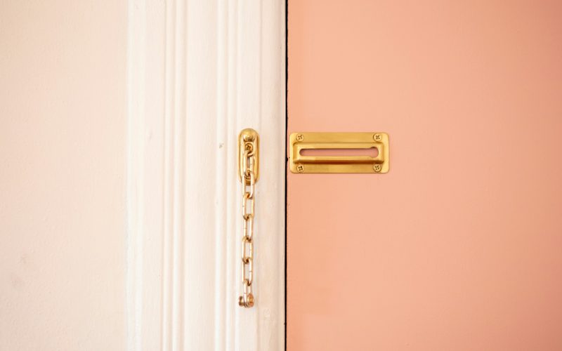A brass security chain beside a closed door in soft light