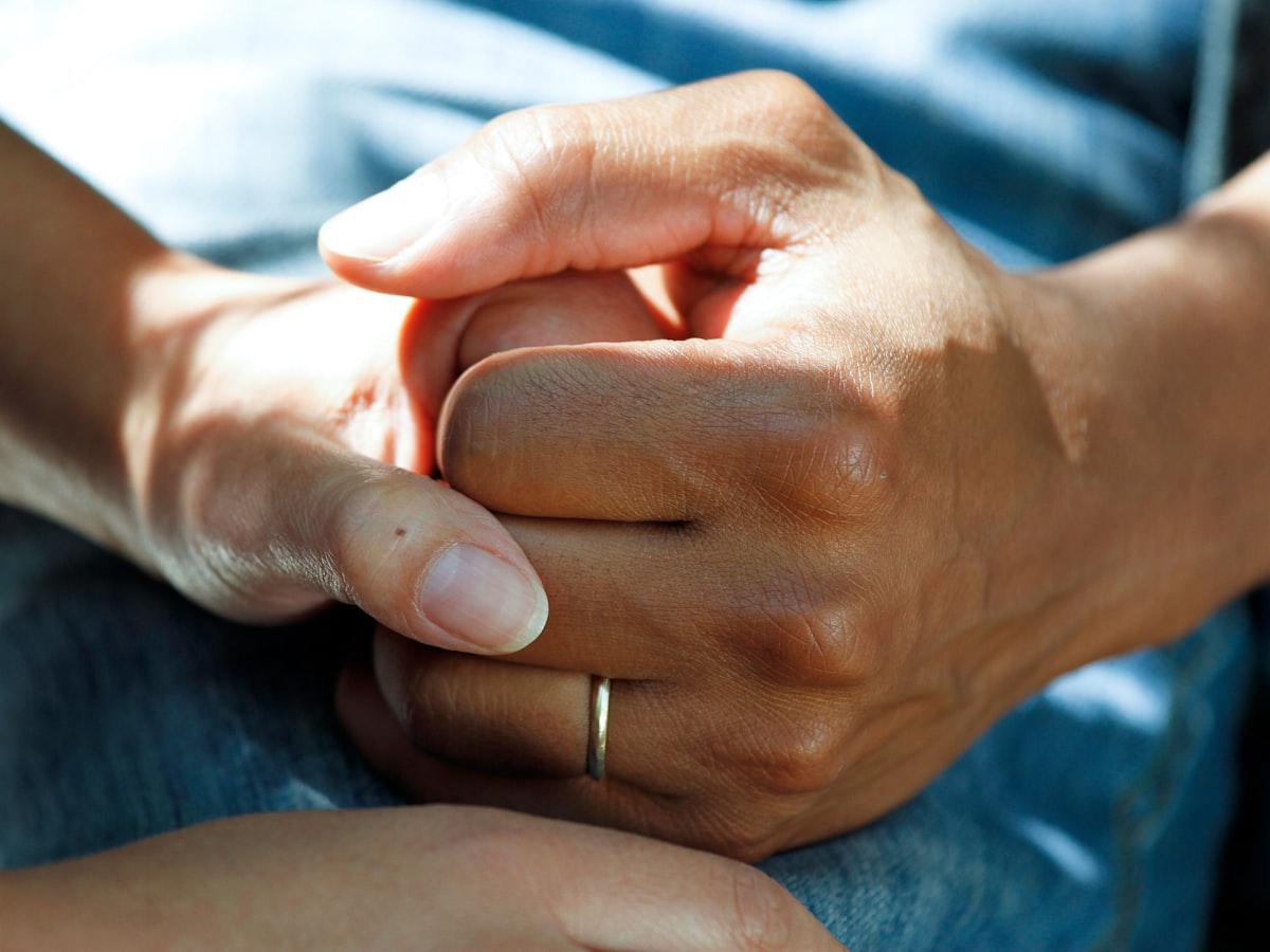 A younger person's hands gently holding an older relative's hands