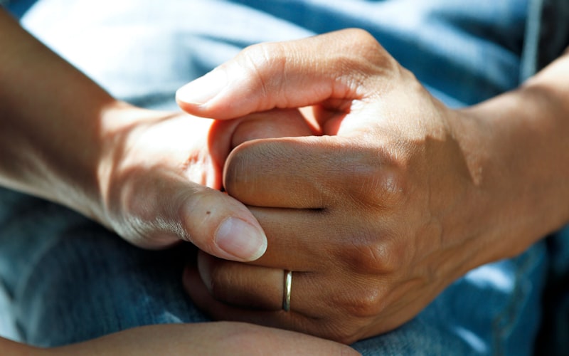 A younger person's hands gently holding an older relative's hands