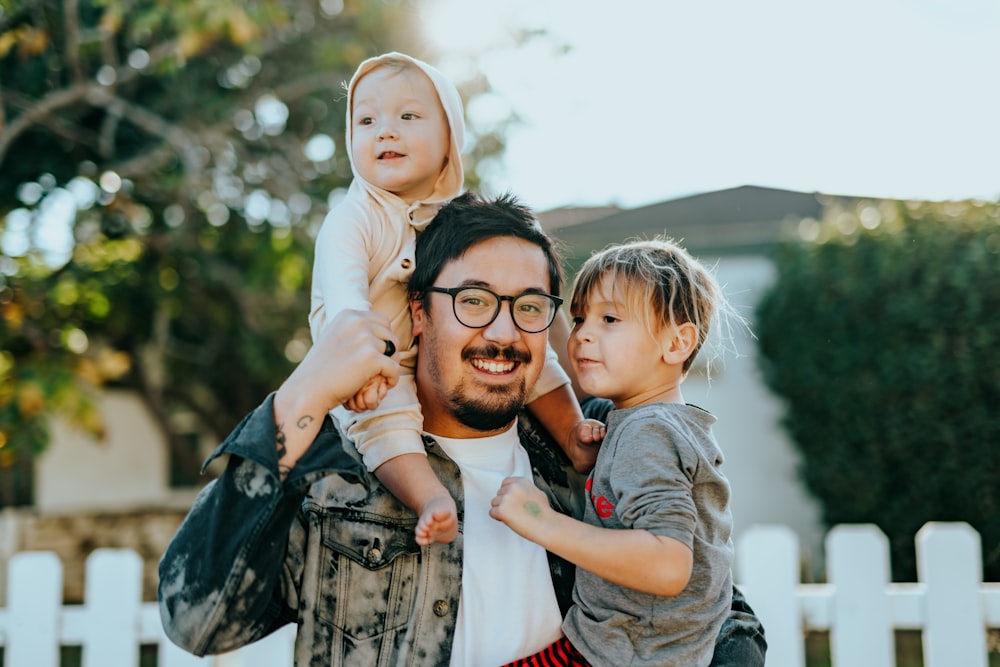 A father outdoors with his two young children, all smiling