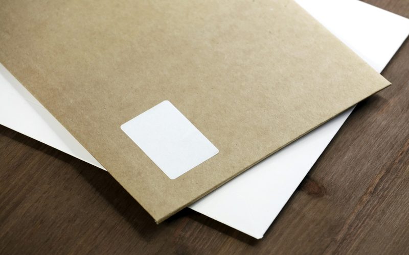 A brown envelope and a white envelope on a wooden table