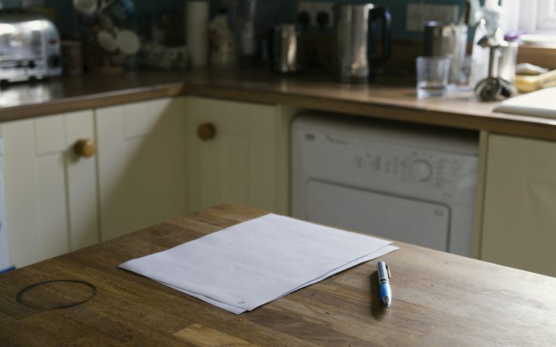 Papers and a pen on a kitchen bench at home
